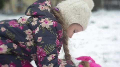 Kid Sits to a Ground Grabs the Heap of Snow Winter Little Girl is Raising up Stock Footage 59780901
