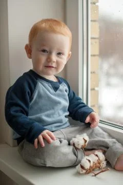 Kid sits on a windowsill Stock Photos