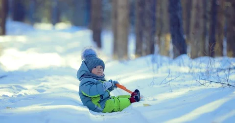 Kid is sitting in the snow. He eats snow with mittens Stock Footage 99603320