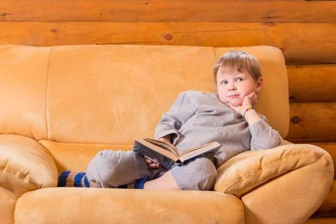 Kid sitting on sofa with a book Stock Photos