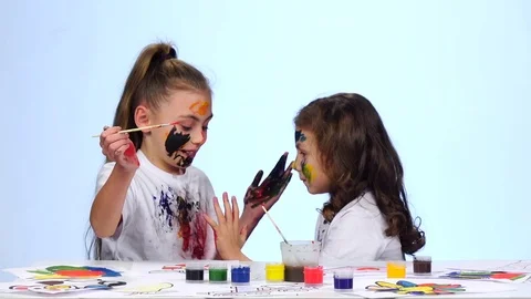 Kid sitting at the table applying paints to their clothes. White background Vidéo 76131062