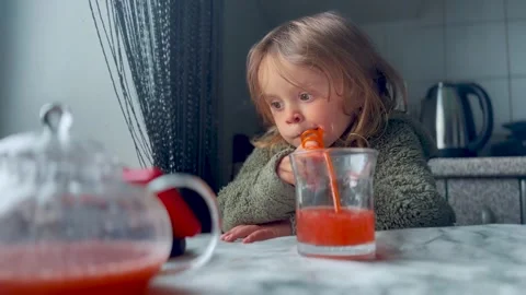 Kid Sitting at Table Drinking Juice from Glass Video stock 333149628