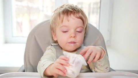 The kid is sitting at the table with a spoon 스톡 동영상 149113616