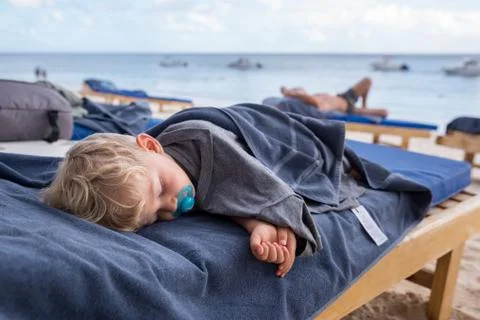 Kid sleeping on deckchairs at the beach 写真素材