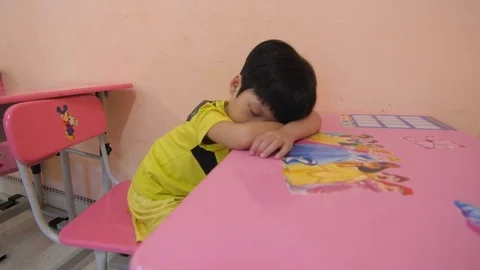 Kid sleeping on a desk in a primary school in Vietnam Stock Footage 75888534