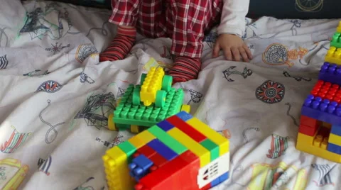 Kid in sleepwear playing constructor on the bed Stock Footage 61329870