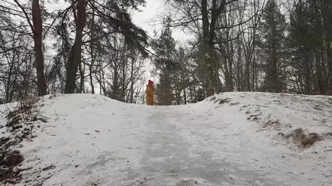 Kid slides down on the ice on snow mountain hil Stock Footage 297849058