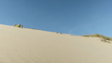 Kid sliding down sand dune Stock Footage 79276515