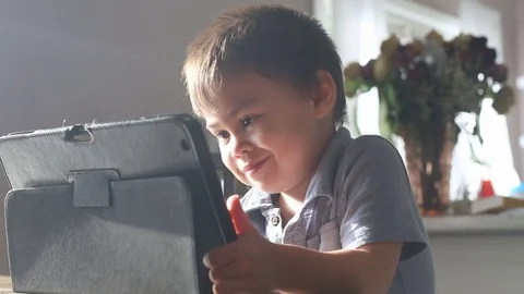Kid smiles while using electronic tablet, video Stock Footage 79720402