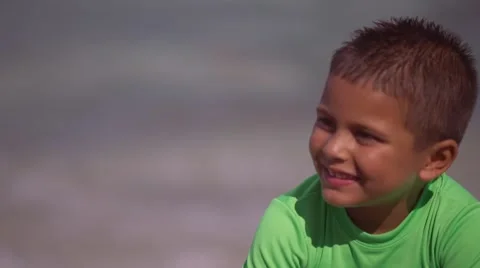 Kid Smiling at his Mom while Playing with Sand in front of Ocean at the Beach Stock Footage 42749018