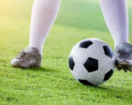 Kid soccer player jogging with control ball to shoot to goal on artificial tu Stock Photos