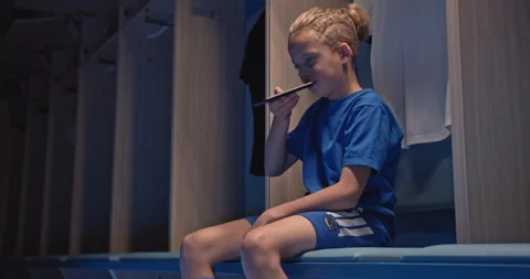 Kid soccer player, man talking with phone sitting in the locker room at the gym Stock Footage 139205363