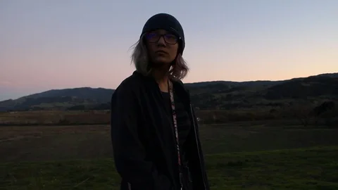 Kid standing away from crowd and watches with mountains behind her Stock Footage 122356233