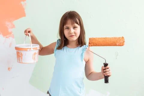Kid standing with paint roller in hand. She is painting the wall. Redecoration Stock Photos