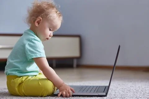 Kid is studying a laptop in an empty bright room. copy space. Stock Photos