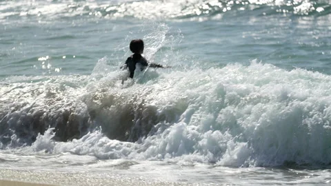 Kid in surf suit plays at the beach. Video stock 236532590