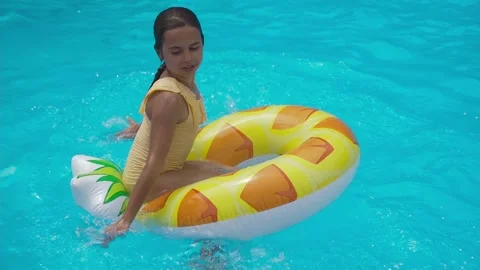 Kid swim on inflatable pineapple ring in pool of the water park. Cheerful girl 動画素材 157773916