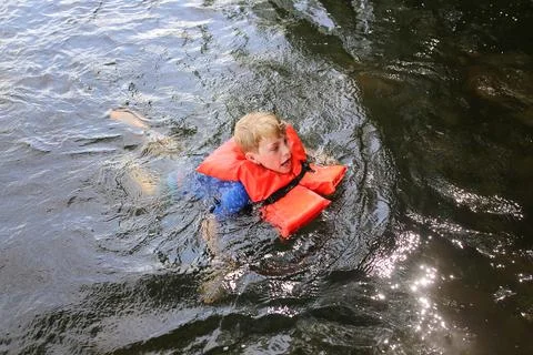 Kid Swimming in Lake Water Looking Distressed and Wearing a Life Vest Stock Photos