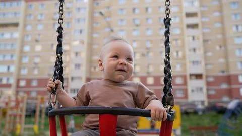 The kid on a swing for the first time in his life gets a lot of fun. Little.. Stock Photos