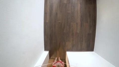 Kid swinging on a swing that hangs on a horizontal bar. At home. View from the Video stock 69893558