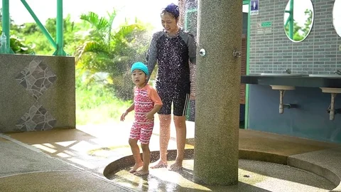 Kid take a shower at swimming pool with her mother Stock Footage 77978452