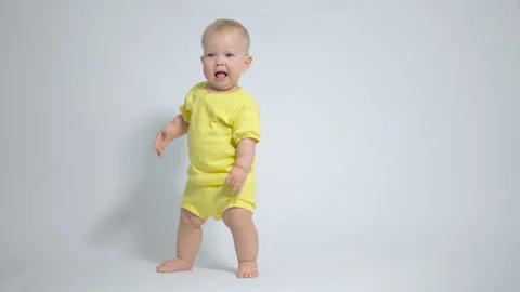 The kid takes the first steps with a smile, trying not to fall and at the sam 스톡 동영상 244837504