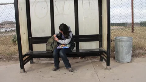 Kid takes out books while waiting for bus Stock Footage 155488226