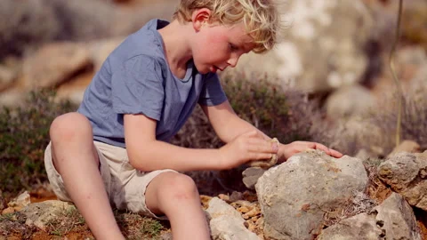 Kid Tapping A Stone Against A Larger Rock Stock Footage 257212830