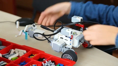 Kid testing his just built computerized robot on table at robotics lesson Stock Footage 87039052