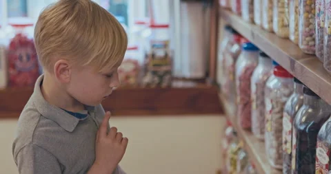 Kid thinking, choice and shopping in a candy store with sweets, confectionery or Stock Footage 335917628