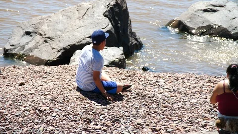Kid throwing rocks into water Slow Motion Lake Superior Duluth Minnesota Stock Footage 94490734