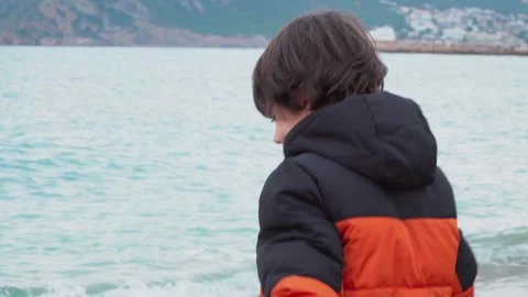 Kid throwing stones from the seaside in winter Stock Footage 284077475