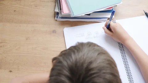 Kid tired writing, do mathematics homework, boy puts his head on hands and do Stock Footage 129668417