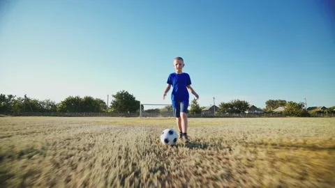 The kid is training to dribble the ball on a large football field. Video stock 147074600