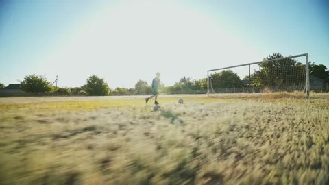 The kid is training to dribble the ball on a large football field. Stockbeeldmateriaal 147074975