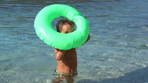 Kid tries to inflate a blown out air ring Stock Footage