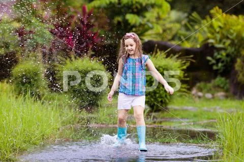 Kid with umbrella playing in summer rain. Stock Photos