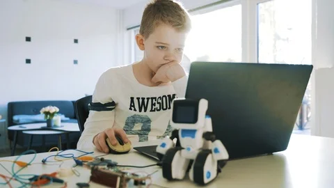 Kid uses a laptop computer and looks concentrated at the screen Stock Footage 102175722