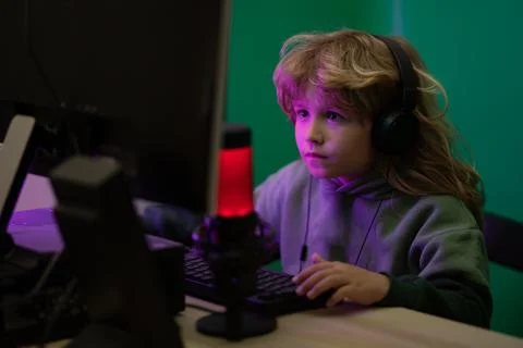 Kid using pc at night. Child with computer in a dark room. A little boy child 写真素材