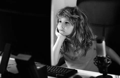 Kid using pc at night. Child with computer in a dark room. Portrait of cute Stock Photos