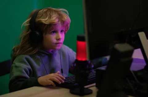 Kid using pc at night. Child with computer in a dark room. A little boy child Stock Photos