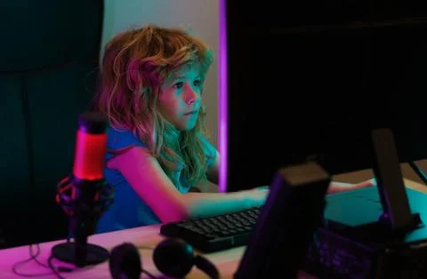 Kid using pc at night. Child with computer in a dark room. Stock Photos