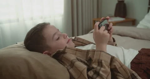 Kid using phone for gaming. Handsome child boy 6 years old playing mobile game Stock Footage 235034550