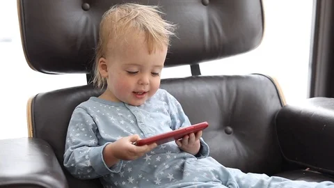 Kid using smartphone sitting in the chair alone Stock Footage 86421524