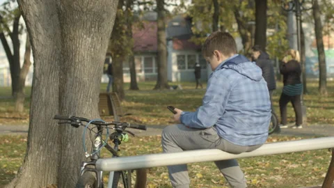 Kid using smartphone while people walking in park Stock Footage 143149225