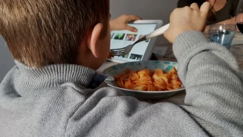 Kid Using Tablet Computer And Eating during a family lunch Stock Footage 82179558