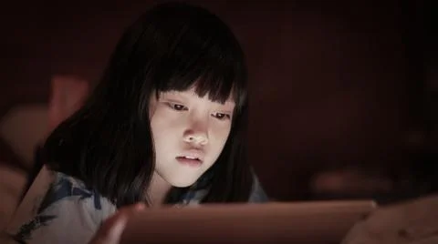 Kid using tablet with light reflex on face. Stock Photos