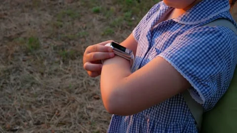 Kid using touchscreen display smartwatch outdoor in park GPS tracker Vídeo Stock 136304025