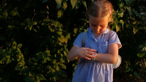 Kid using touchscreen smartwatch outdoor in park. Child talking on vdeo call Stock Footage 136366196