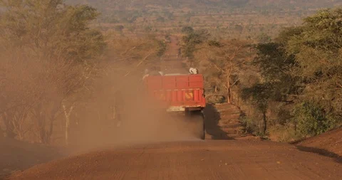 A Kid walk a red truck down  Dirt Road in Rural Africa on a Sunny day in Uganda Stock Footage 109495399
